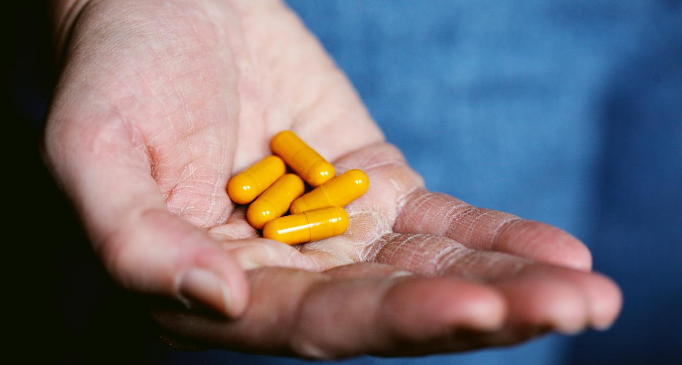 Yellow capsules resting on the palm of a human being