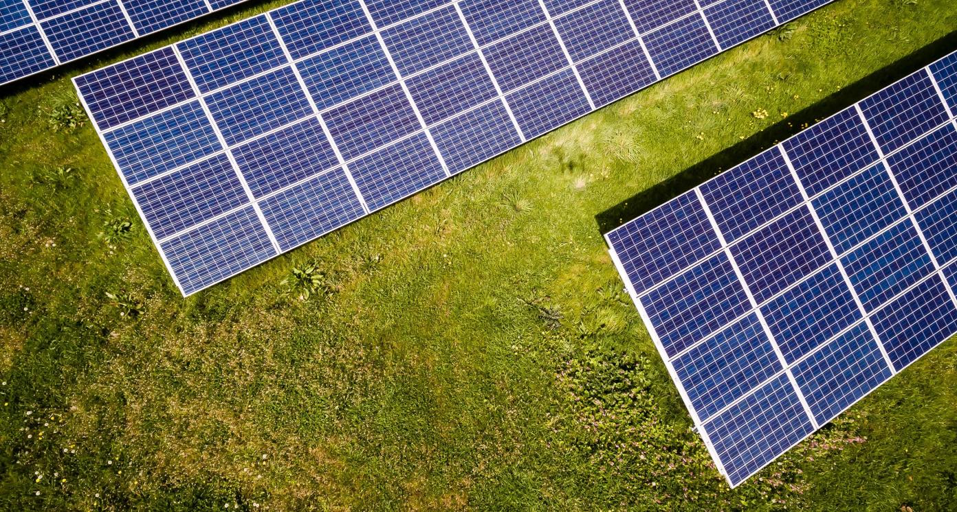 arial view of solar panels on green field, photo by andreas  gucklhorn