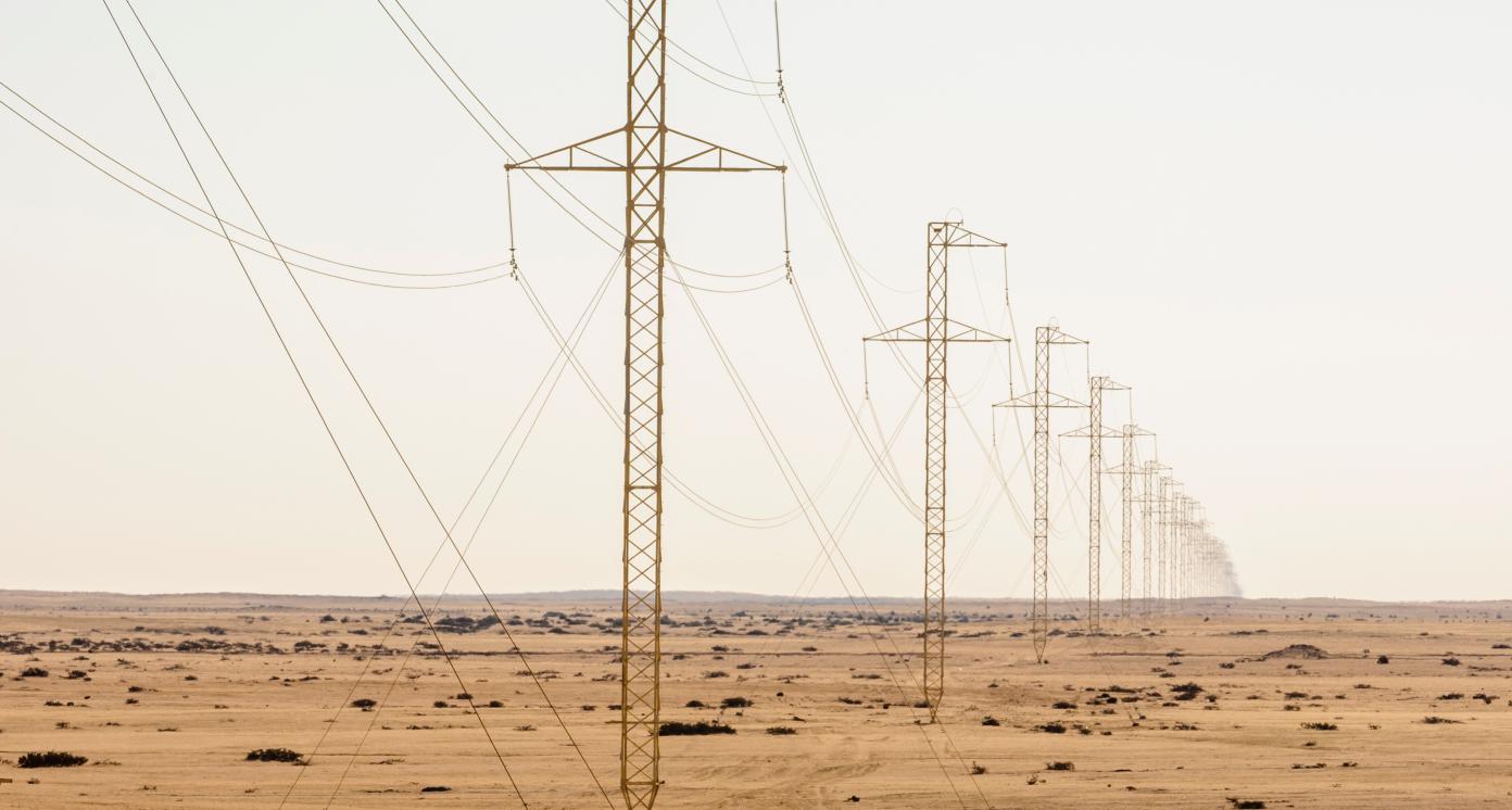 Electricity pylons stretch out as far as you can see, showing the curvature of the earth. Namib Desert, Namibia