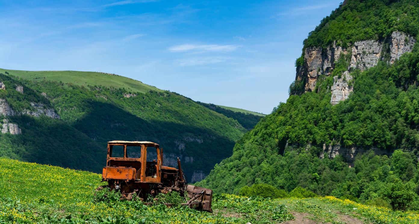 An out of order agricultural tractor with some tree covered rocks in Tavush region of Armenia