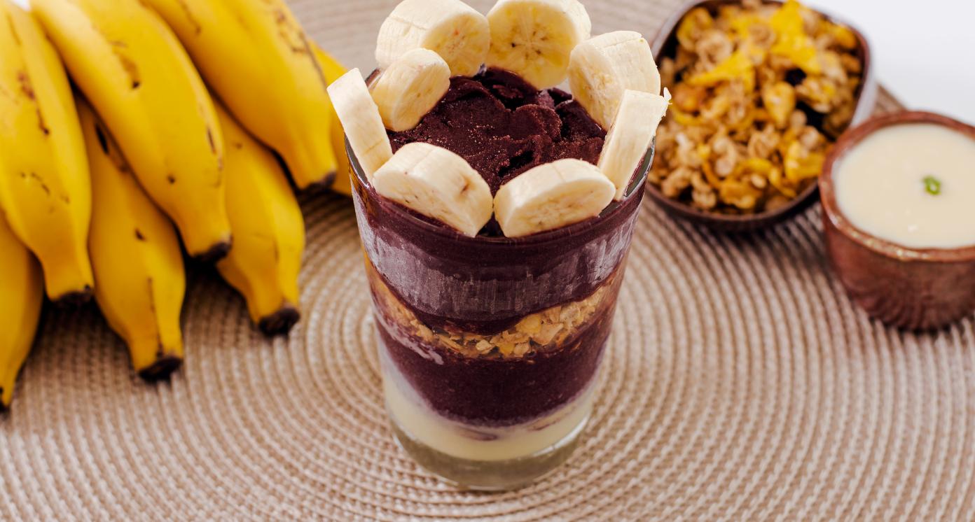 Acaí glass with ingredients and bananas in the background