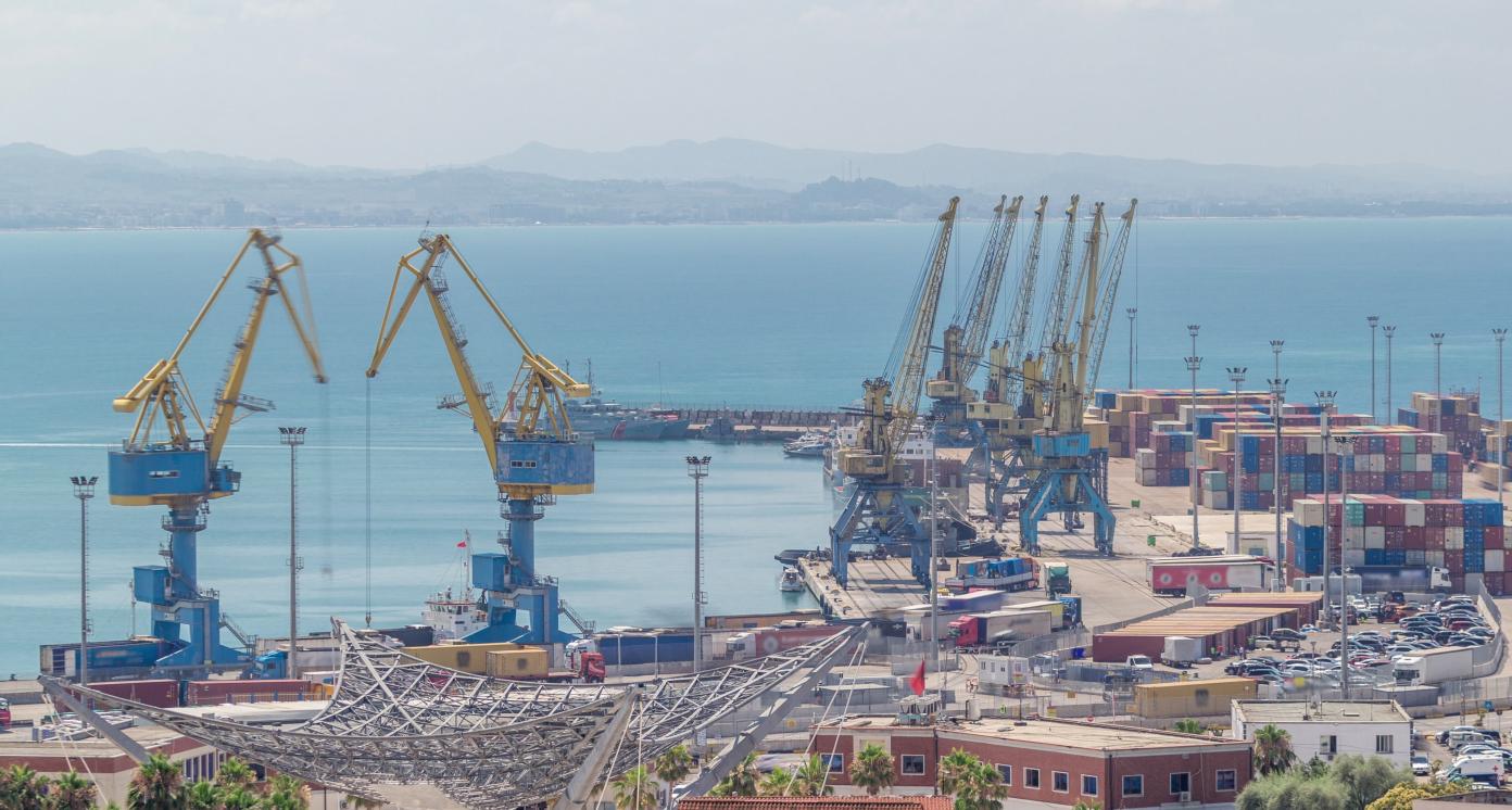 Aerial view from above to the port of Durres in the Adriatic Sea timelapse. A platform for containers surrounded by tower cranes for unloading. In the port there are many cargo trucks moving around