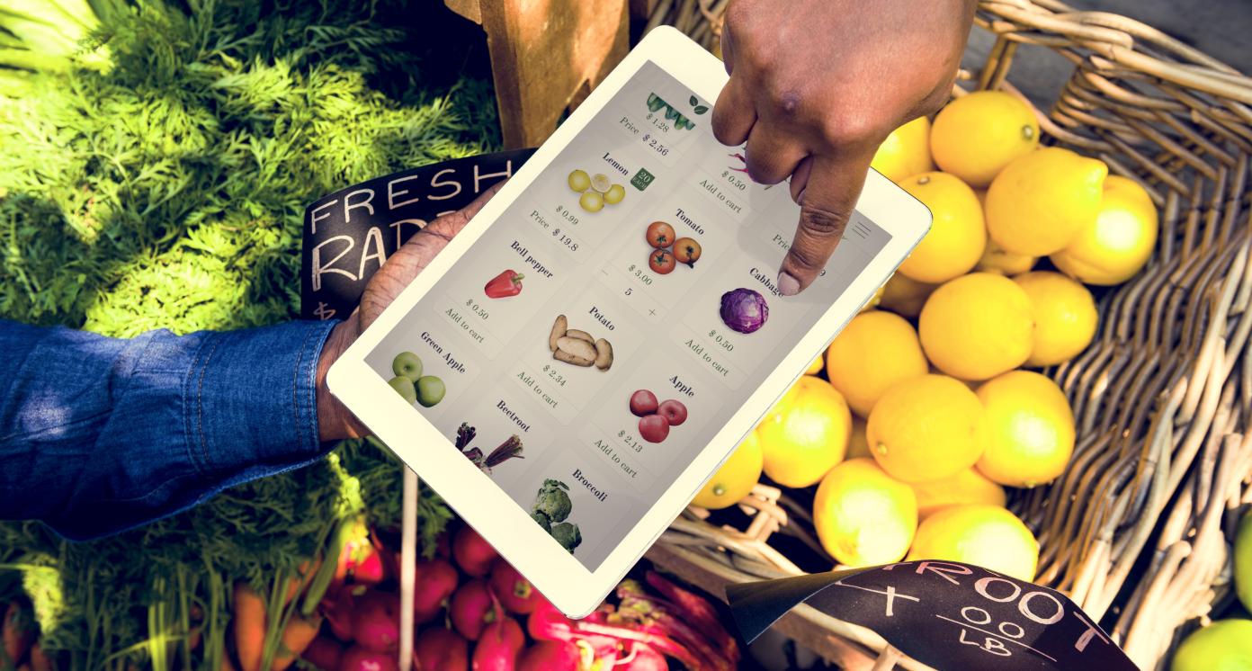 Hand using digital tablet in aerial view on vegetable and fruit