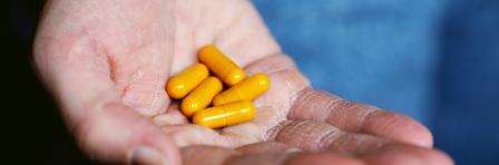 Yellow capsules resting on the palm of a human being