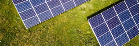 arial view of solar panels on green field, photo by andreas  gucklhorn