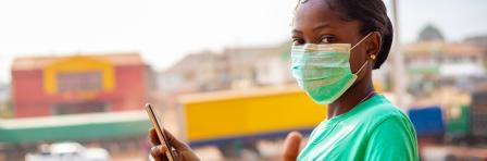 young black African woman doing a thumps up sign holding mobile phone