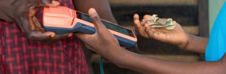 Hands of two african individuals doing business transaction with point of sales terminal know as POS machine in Nigeria