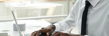 Close-up of African American businessman in white shirt working online on laptop at office