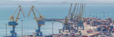 Aerial view from above to the port of Durres in the Adriatic Sea timelapse. A platform for containers surrounded by tower cranes for unloading. In the port there are many cargo trucks moving around