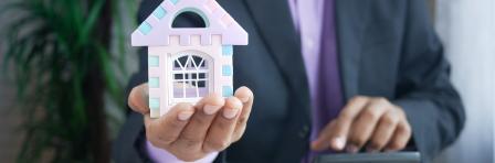 Man in a suit holding a miniature house